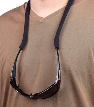 The stretchy nylon retainer is hanging from someone's neck as it holds on to a pair of glasses. The dude is wearing a brown shirt.